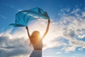 Beautiful young woman holding blue scarf on the wind